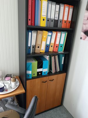 a desk with a chair and bookshelf in the corner
