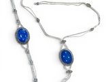 silver necklace with blue stone and tassel on white background
