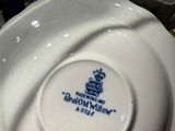 someone is holding a white bowl with a blue crown on it