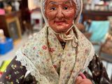 a figurine of an old woman holding a basket of flowers