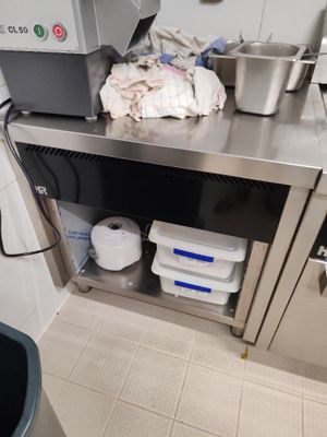 une cuisine équipée d'un plan de travail en inox et d'une poubelle
