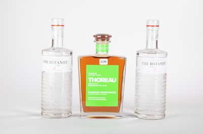 trois bouteilles d'alcool posées les unes à côté des autres sur une surface blanche
