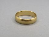 a close up of a gold wedding ring on a gray surface