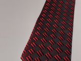 a close up of a red and black tie on a white table