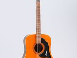 an orange acoustic guitar sitting on a stand against a white background