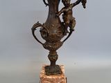 a bronze vase on a marble base with two cherenshes on it