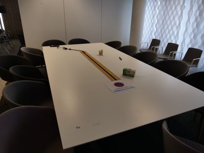 une longue table sur laquelle est posé un crayon, au milieu d'une pièce
