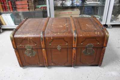 a brown trunk sitting on the floor in front of a glass case