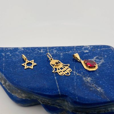 gold plated pendants and earrings on a blue stone