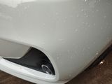 a close up of a white car with water droplets on it