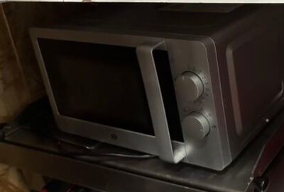 a microwave sitting on top of a metal shelf