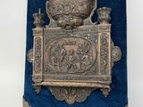 a metal plaque with a pipe, pipe holder and other items on it