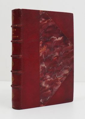 un vieux livre à la couverture rouge posé sur une table blanche