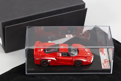 une petite voiture rouge dans une boîte transparente posée sur un tissu noir