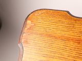 a close up of a wooden chair with a clock in the background