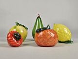 trois figurines représentant différents fruits et légumes posées sur une table