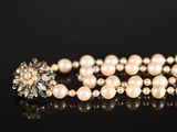 a close up of a pearl necklace on a black surface