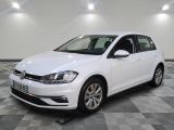 Une Volkswagen Golf blanche est garée dans une pièce dont le sol est en damier.