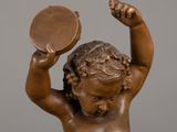 a bronze statue of a child holding a mirror in his hand