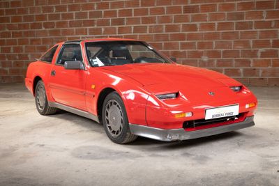 an image of a red sports car parked in front of a brick wall