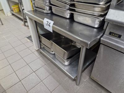several pans are stacked on a metal shelf in a commercial kitchen