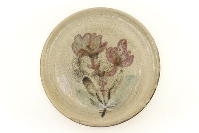 une petite assiette décorée de fleurs, posée sur un fond blanc