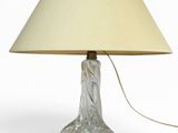 une lampe en verre munie d'un abat-jour beige