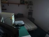 une pièce faiblement éclairée dans laquelle se trouvent un lit, un bureau et une télévision