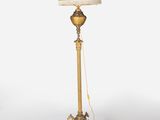 an antique brass floor lamp with a white shade on top of it