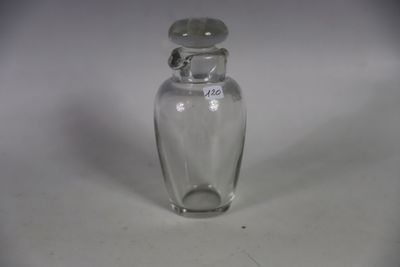 une petite bouteille en verre avec un bouchon argenté, posée sur une surface blanche