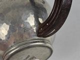 a silver tea pot with a handle on a table