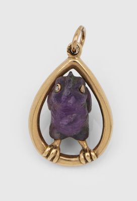un gros plan sur une pierre violette sertie dans un pendentif plaqué or