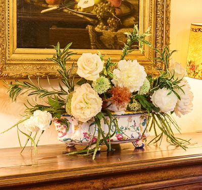 un vase de fleurs posé sur une table devant un tableau