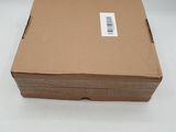 une boîte en carton sur laquelle est collé un autocollant, posée sur une surface blanche