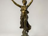 une statue antique en bronze représentant une femme les mains levées