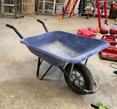 une brouette bleue dans un garage, avec des outils par terre