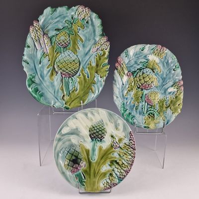 trois assiettes décoratives ornées de motifs, posées sur un socle transparent
