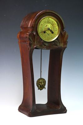 une horloge en bois avec un cadran vert, posée sur un socle