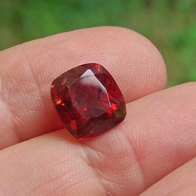 une personne tient un diamant rouge dans la main, sur un fond vert