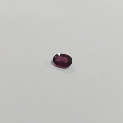 an oval cut purple garnet stone on a white surface