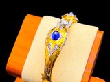 yellow gold bracelet with sapphire and diamonds on display on wooden stand