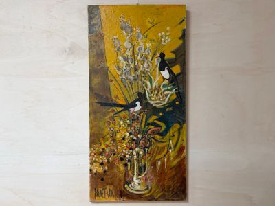 un tableau accroché au mur d'une pièce où se trouve un vase de fleurs