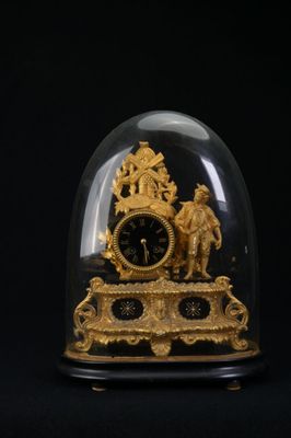 une horloge dorée sous un dôme en verre sur fond noir