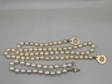 a close up of a white pearl necklace with a gold clasp