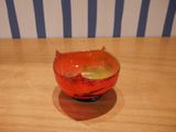 un bol rouge posé sur une table en bois, avec en arrière-plan un mur rayé de bleu et de blanc