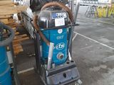 a blue machine that is sitting next to a pile of wood
