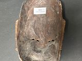 a wooden mask on a table with a tag on it