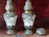 two silver vases sitting on top of a table