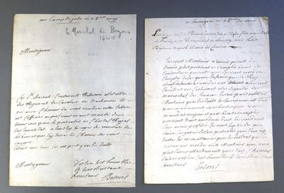 deux feuilles de papier couvertes d'écriture, posées sur une table
