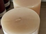 Plusieurs bougies sont alignées sur une étagère, à côté d'une bouteille de vin